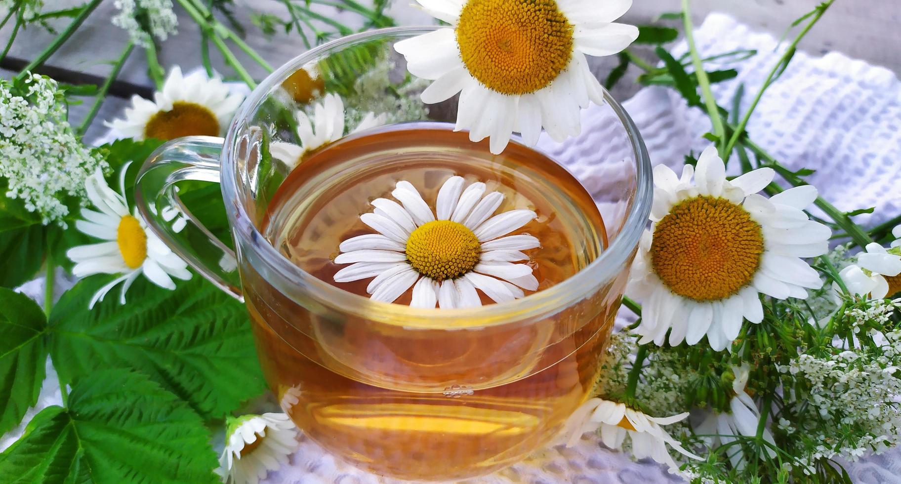 camomilla e fiori. tazza di tè su uno sfondo di legno foto