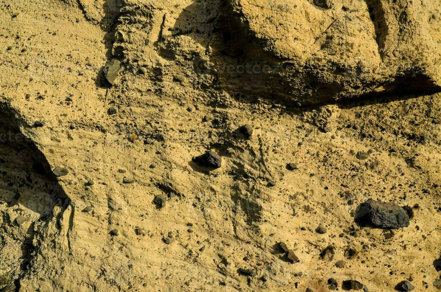 un' roccia parete con nero e giallo rocce foto