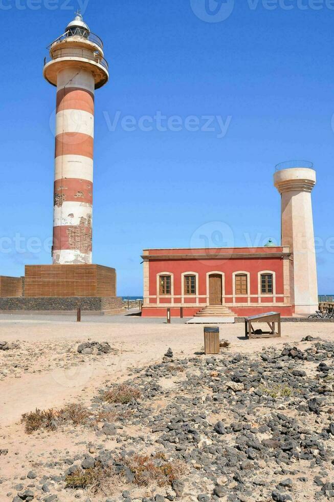 un' faro su il spiaggia con un' rosso edificio foto