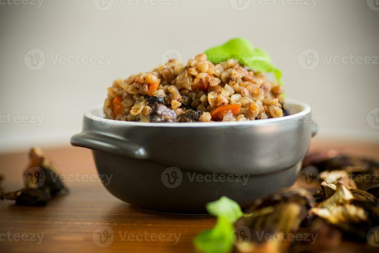 bollito grano saraceno con verdure e secco foresta funghi nel un' ceramica muffa foto