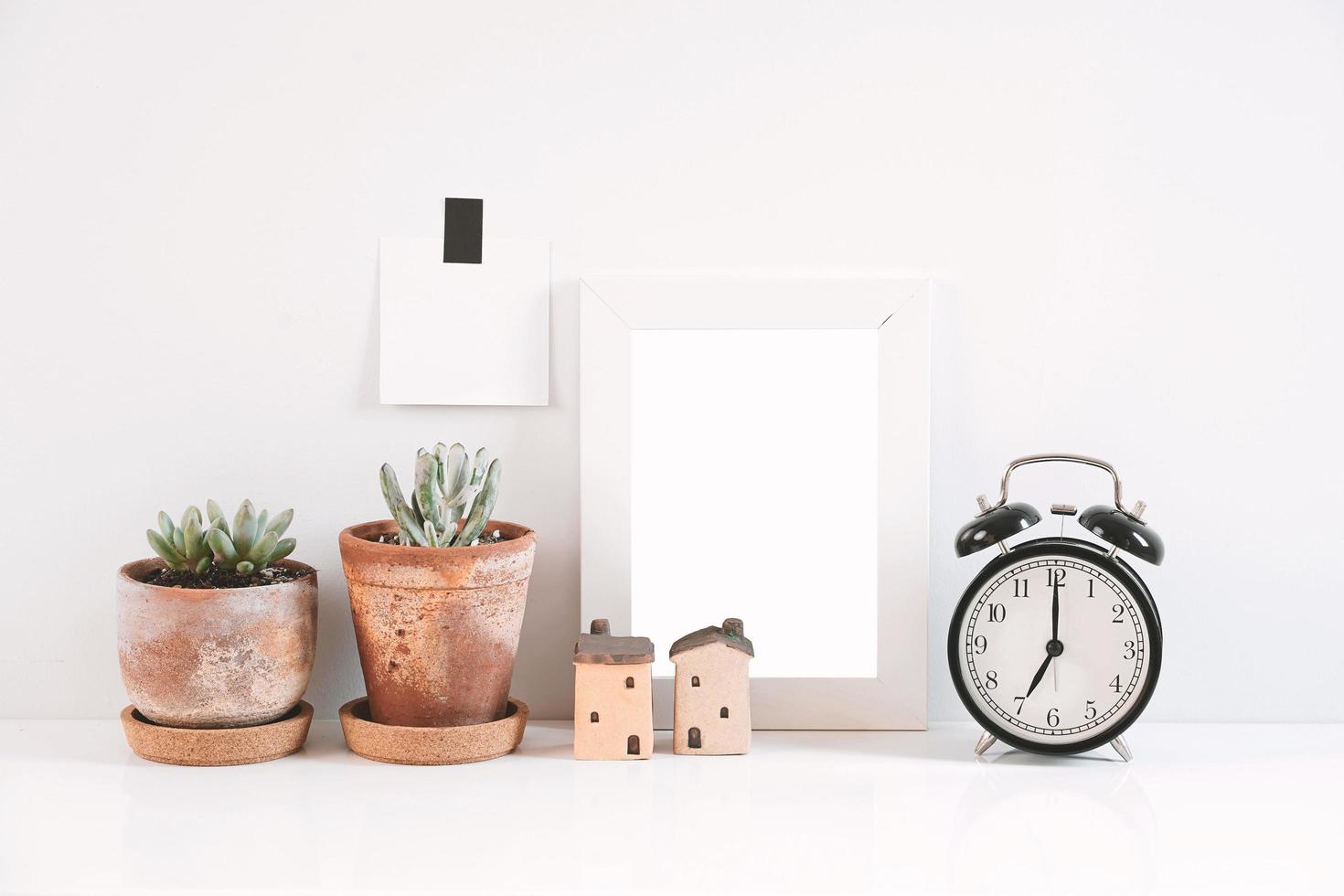 piante grasse o cactus in vasi di argilla su sfondo bianco sul tavolo con l'orologio e la cornice foto