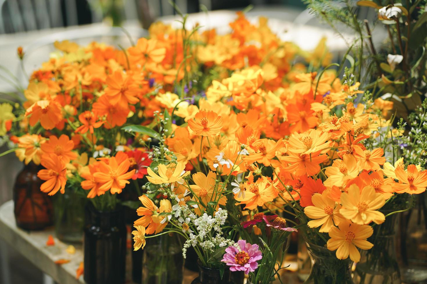 bellissimi fiori in una bottiglia di vetro marrone posta su un tavolo in giardino al mattino foto