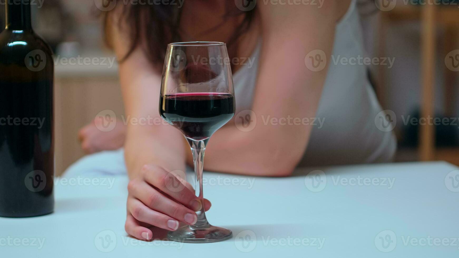 vicino su di donna Tenere un' bicchiere di rosso vino su il tavolo. infelice persona sofferenza di emicrania, depressione, malattia e ansia sensazione esausto con vertigini sintomi avendo alcolismo i problemi. foto