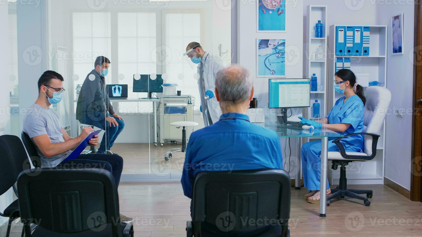 medico dando infermiera paziente radiografia mentre finitura malato uomo visita medica nel il suo ufficio. assistente con viso maschera contro covid19 spingendo Disabilitato donna nel sedia a rotelle attraverso in attesa la zona. foto