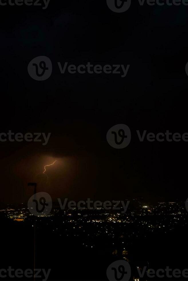 un' fulmine bullone è visto al di sopra di un' città a notte foto