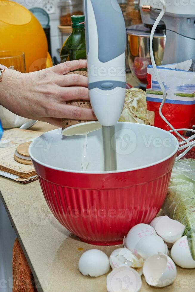 casalinga sbattere pancake pastella nel cucina con miscelatore e ciotola foto