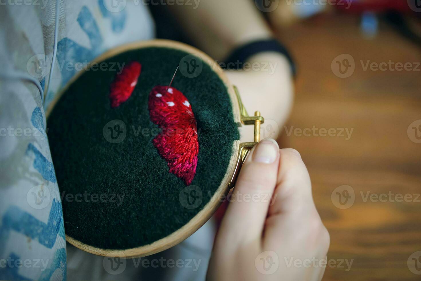 femmina è ricamo fungo berretto su verde stoffa. ragazza cucire filo con discussioni a casa su un di legno telaio. fatto a mano, mestiere, passatempo. foto