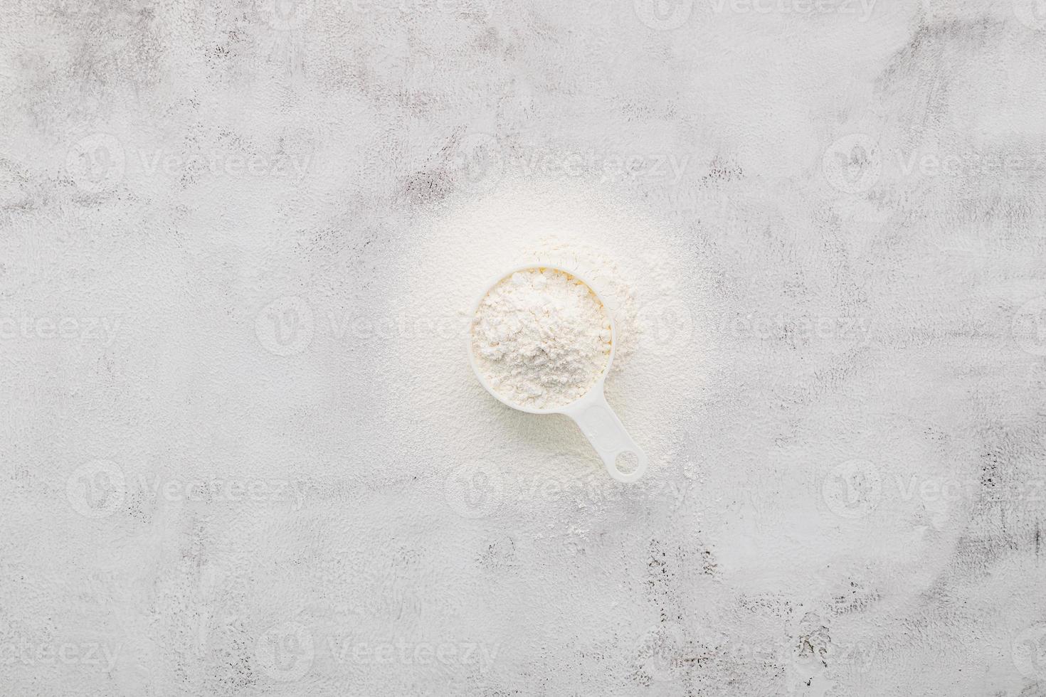 gli ingredienti per la pasta della pizza fatta in casa misurino farina di frumento impostata su sfondo di cemento bianco. foto