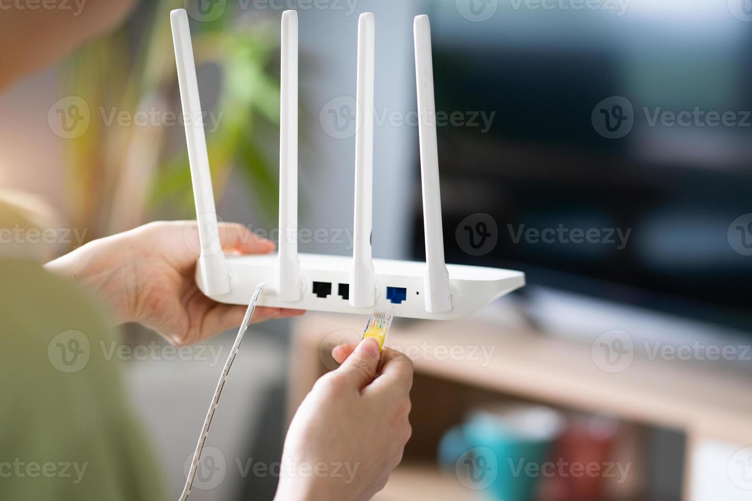 ragazza asiatica sta collegando il cavo di rete al trasmettitore wifi foto