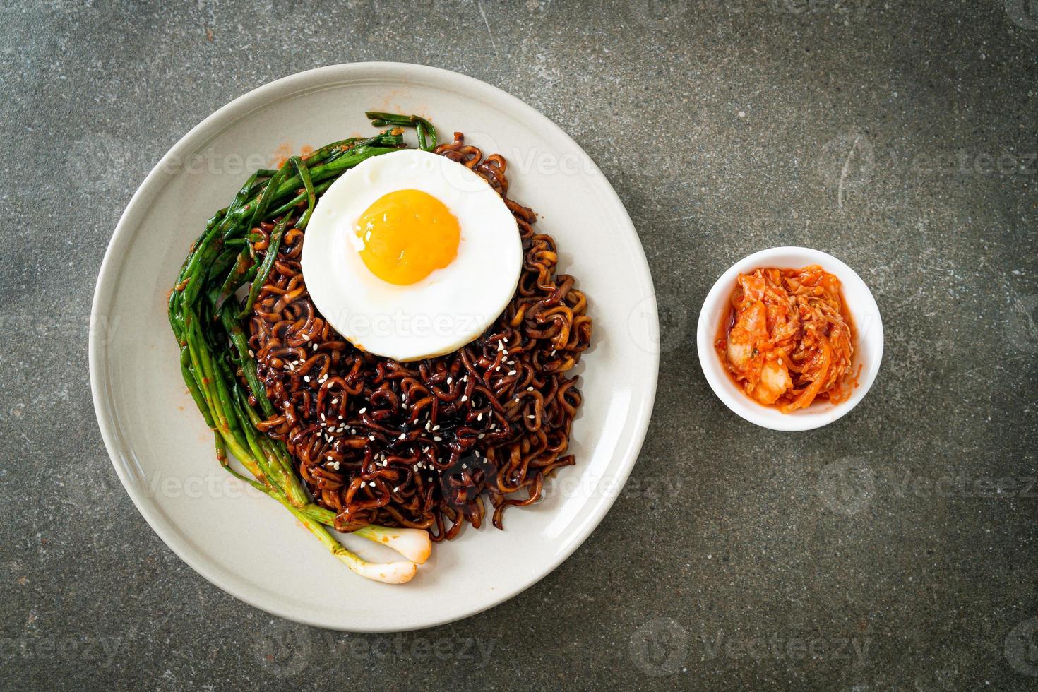 noodles istantanei con salsa nera piccante coreana essiccata con uovo fritto e kimchi foto