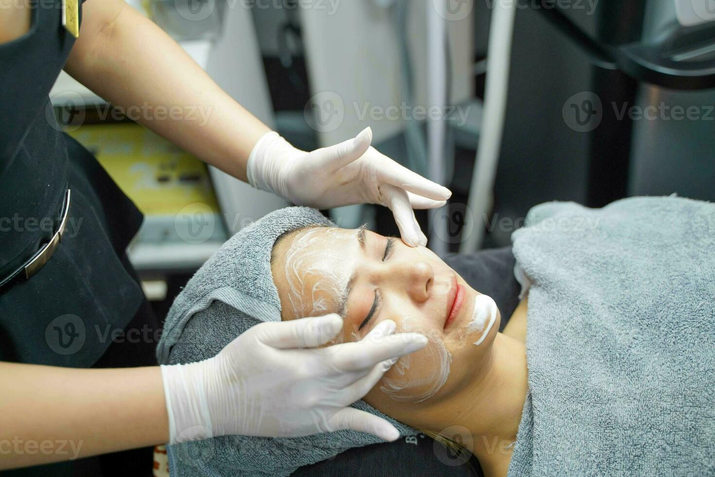avvicinamento cosmetologo l'applicazione liscio facciale bianca maschera crema e massaggio su bellezza donna fabbricazione viso terme nel bellezza clinica. foto