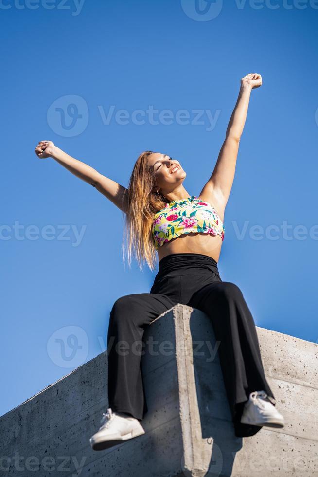 giovane donna che apre le braccia contro il cielo blu foto