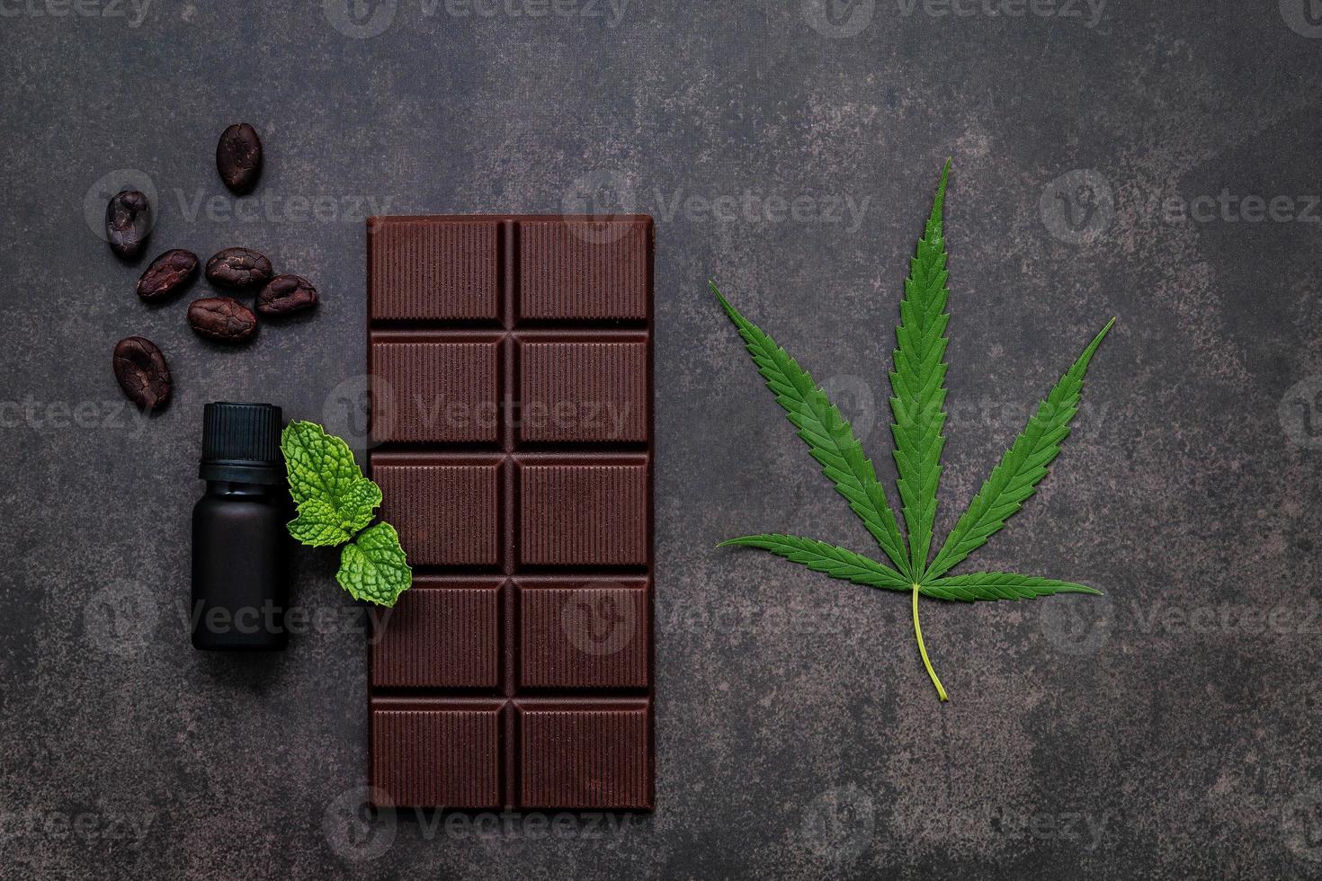 immagine concettuale di cibo di foglia di cannabis con cioccolato fondente e forchetta su sfondo di cemento scuro. foto