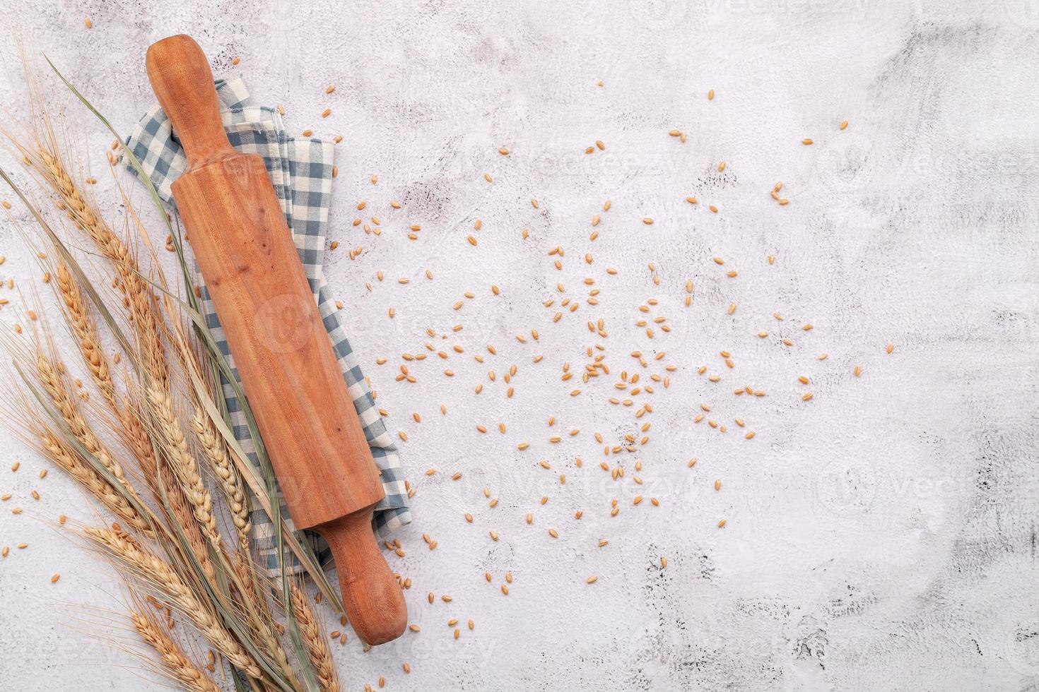 spighe di grano e chicchi di grano setup con mattarello su sfondo di cemento bianco. foto