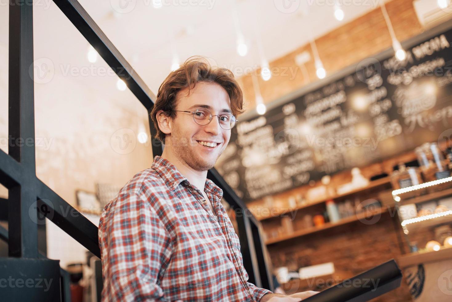 premuroso giovane è seduto in pasticceria. sta bevendo caffè mentre aspetta qualcuno foto