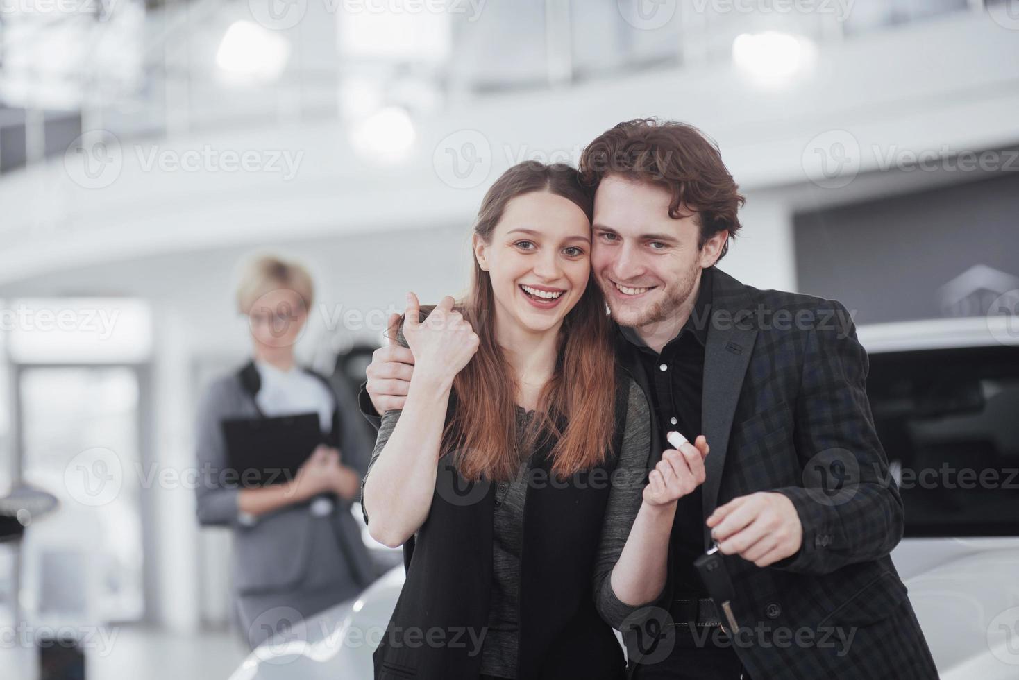 orgogliosi proprietari. bella giovane coppia felice che si abbraccia in piedi vicino alla loro auto appena acquistata sorridendo con gioia mostrando le chiavi della macchina alla fotocamera copyspace famiglia amore relazione stile di vita acquisto consumismo foto