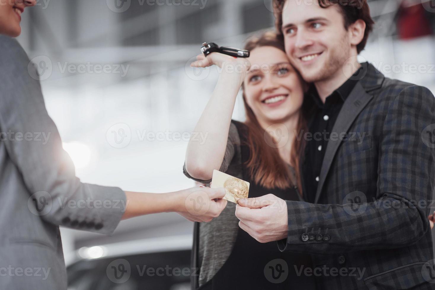orgogliosi proprietari. bella giovane coppia felice che si abbraccia in piedi vicino alla loro auto appena acquistata sorridendo con gioia mostrando le chiavi della macchina alla fotocamera copyspace famiglia amore relazione stile di vita acquisto consumismo foto