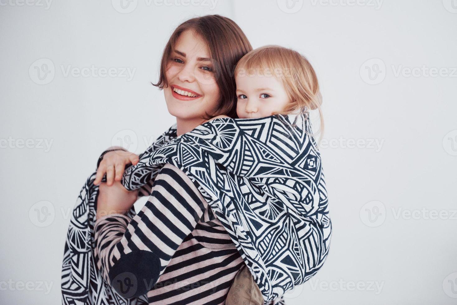 moderna giovane madre che trasporta il suo bambino in una fionda foto
