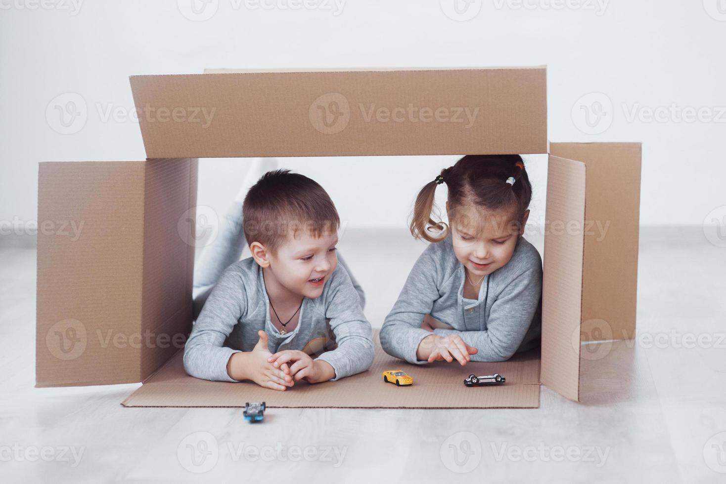 fratellino e sorellina che giocano in scatole di cartone nella scuola materna foto