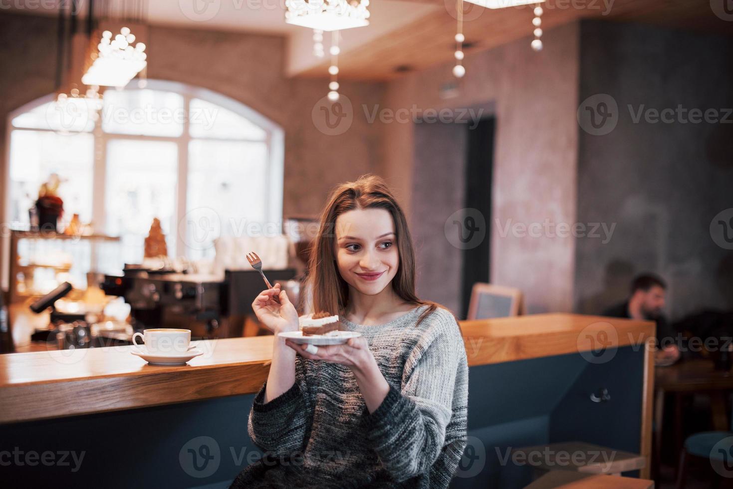 giovane donna sorridente felice che utilizza il telefono in un caffè. bella ragazza in colori primaverili alla moda foto