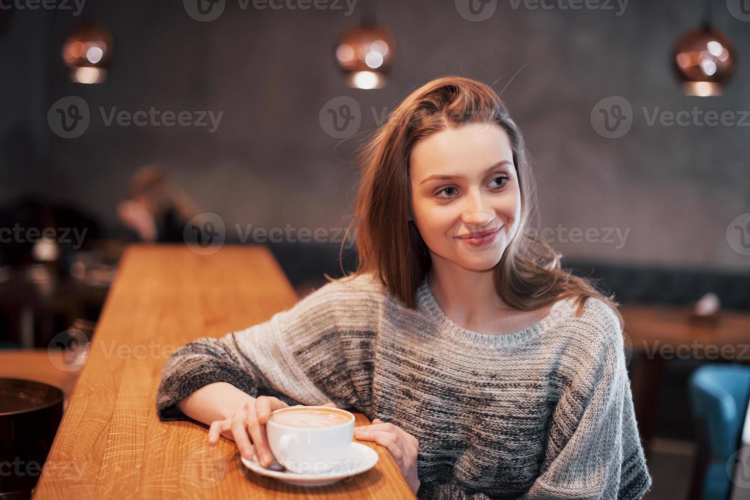 bella giovane donna seduta al bar con una tazza di tè foto
