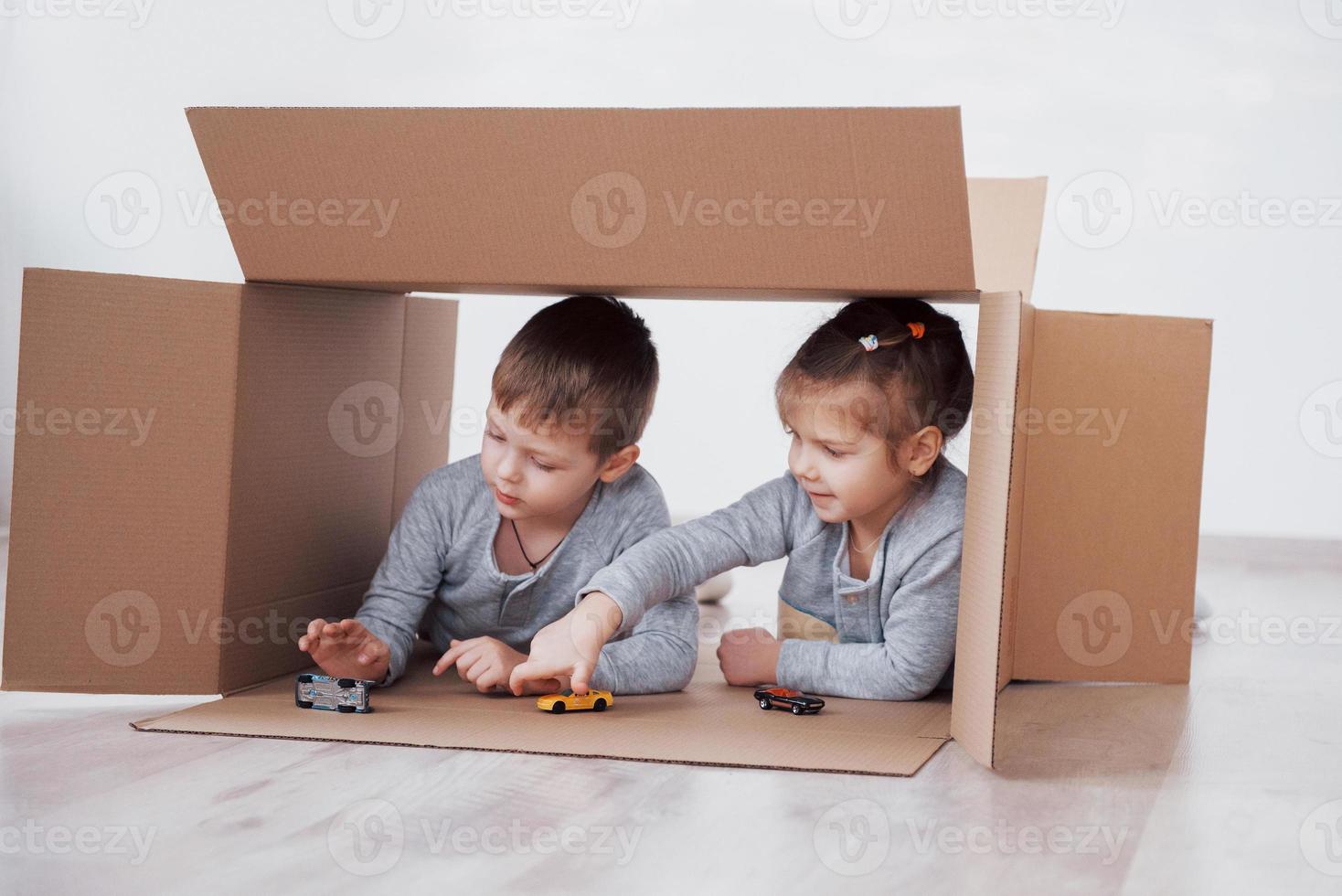 fratellino e sorellina che giocano in scatole di cartone nella scuola materna foto