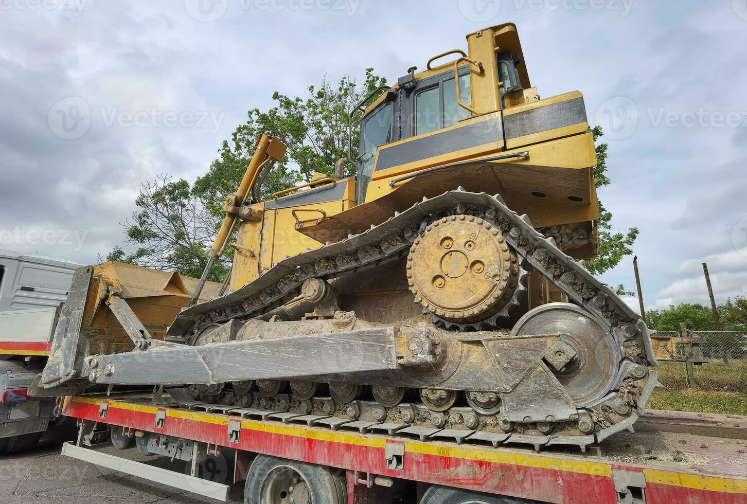 trailer camion con lungo piattaforma trasporto il escavatore. terra motore terna su pesante dovere flatbed veicolo per trasportato. foto
