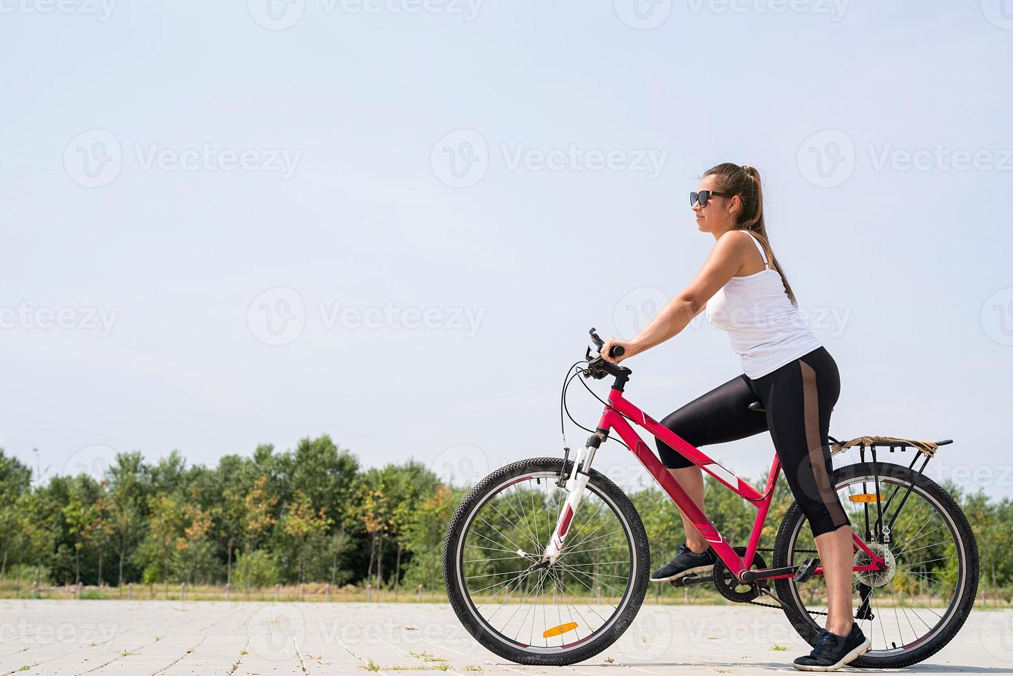 donna spensierata in sella a una bicicletta in un parco foto