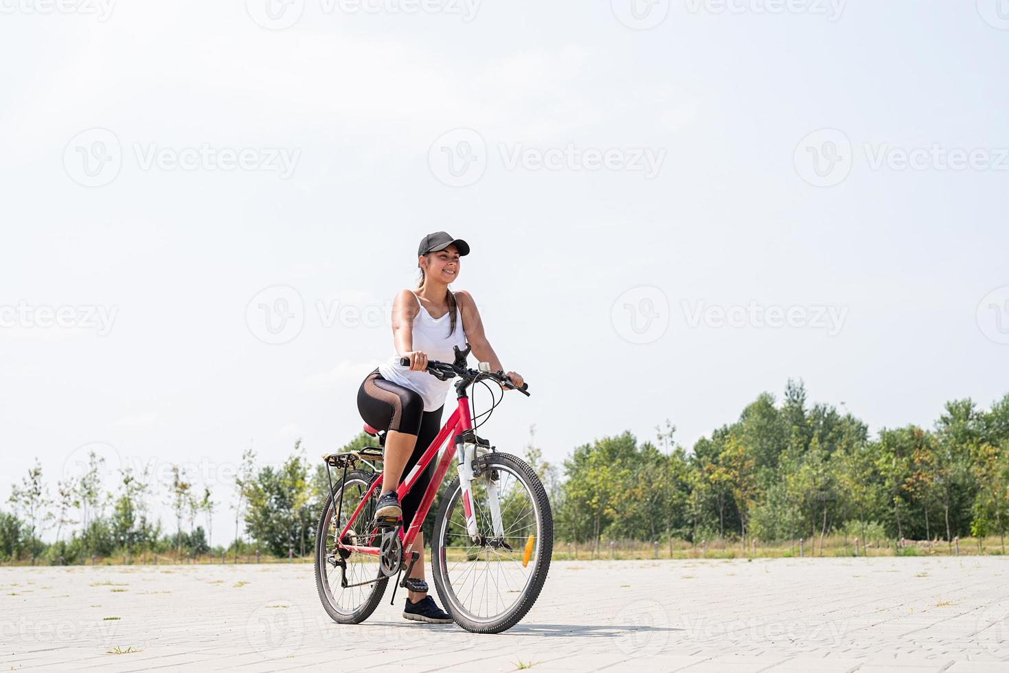 donna spensierata in sella a una bicicletta in un parco foto