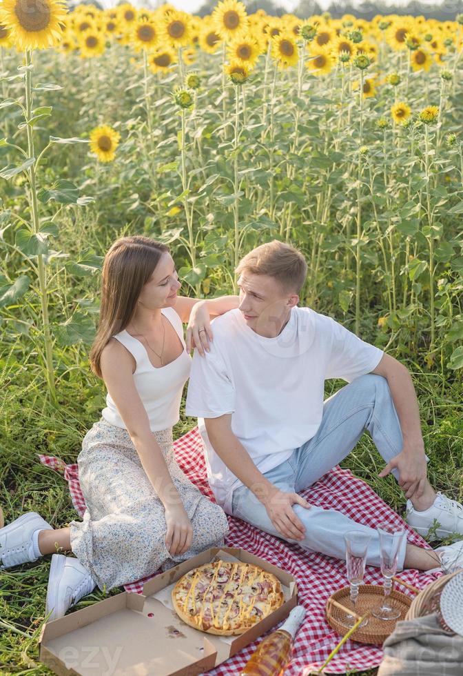 giovane coppia che fa picnic sul campo di girasoli foto