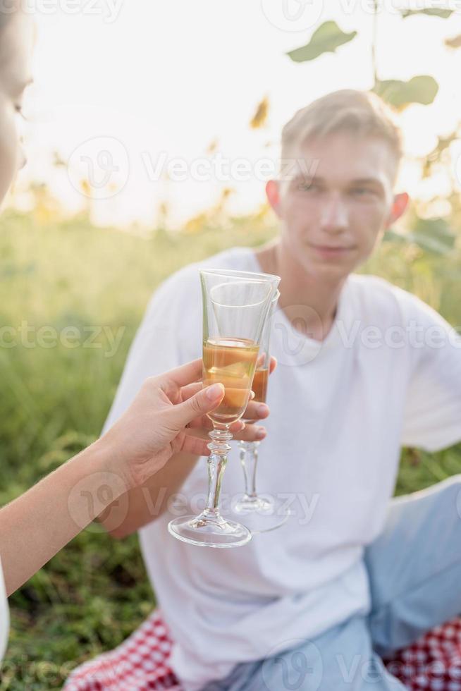 giovane coppia che fa picnic sul campo di girasoli al tramonto foto