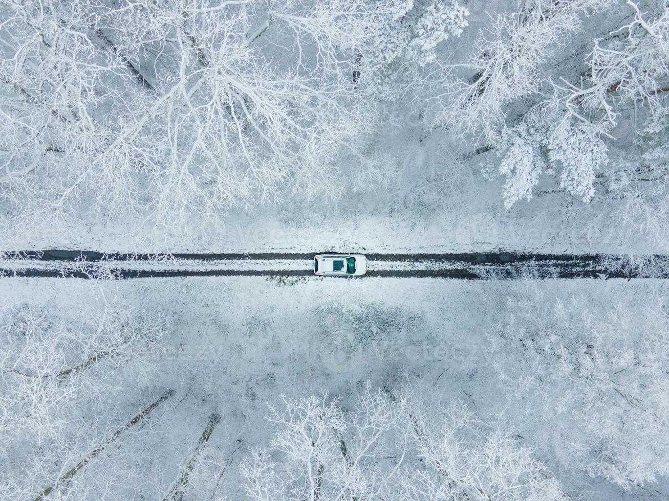 vista dell'auto bianca dall'alto nella foresta invernale ghiacciata foto