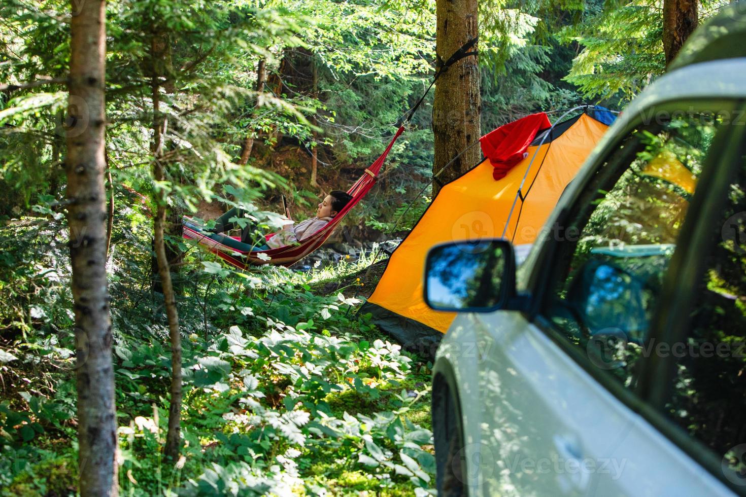 donna sdraiata nell'amaca tenda e auto sullo sfondo foto