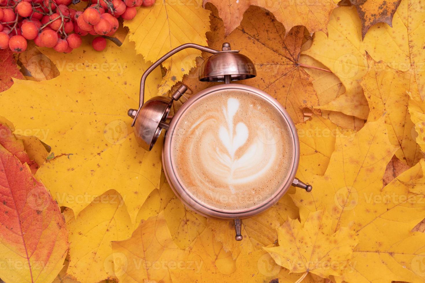 arte del caffè in una sveglia su uno sfondo di foglie cadute. tempo autunnale e concetto di caffè mattutino foto
