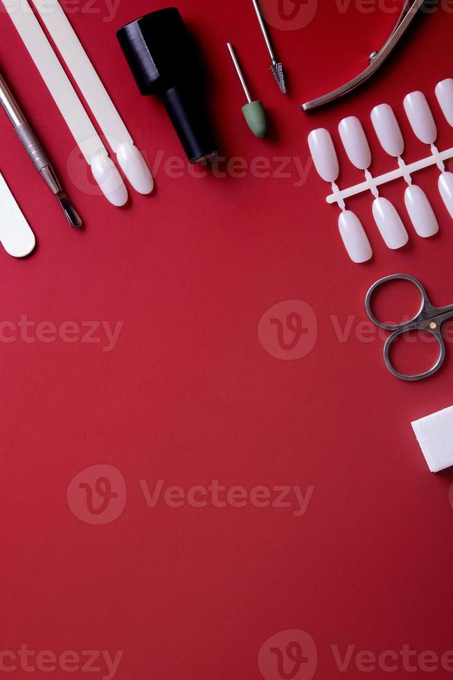 strumenti per manicure e suggerimenti su sfondo rosso con spazio di copia foto