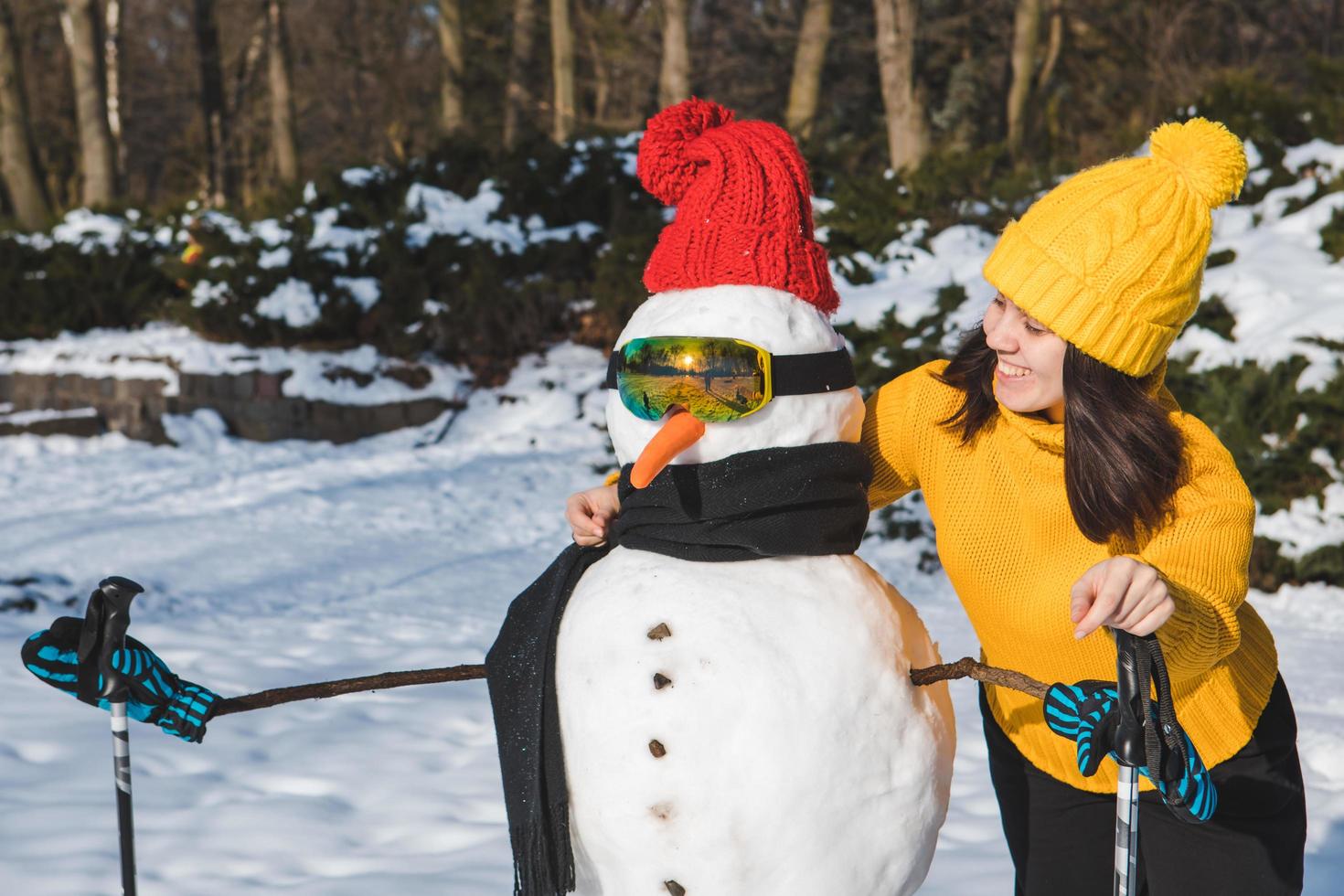 donna sorridente vicino al pupazzo di neve dello sciatore foto