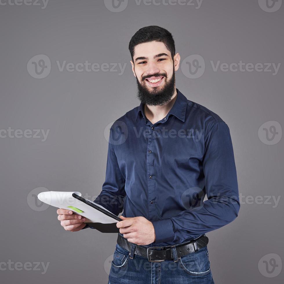 concentrato giovane uomo d'affari attraente in camicia blu che pianifica e scrive negli appunti foto