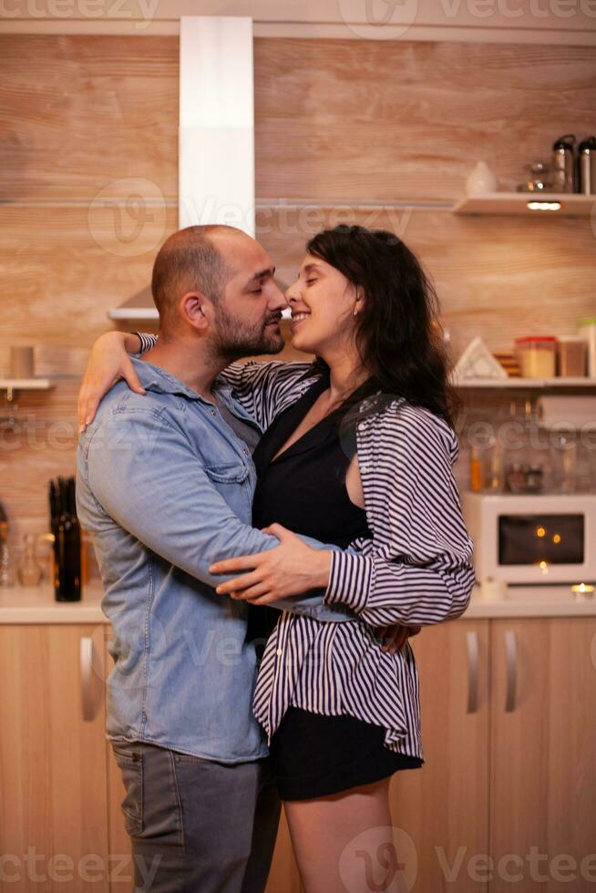 coppia sensazione bene mentre danza nel cucina durante cena. contento nel amore coppia cenare insieme a casa, godendo il pasto, sorridente, avendo divertimento, festeggiare loro anniversario. foto