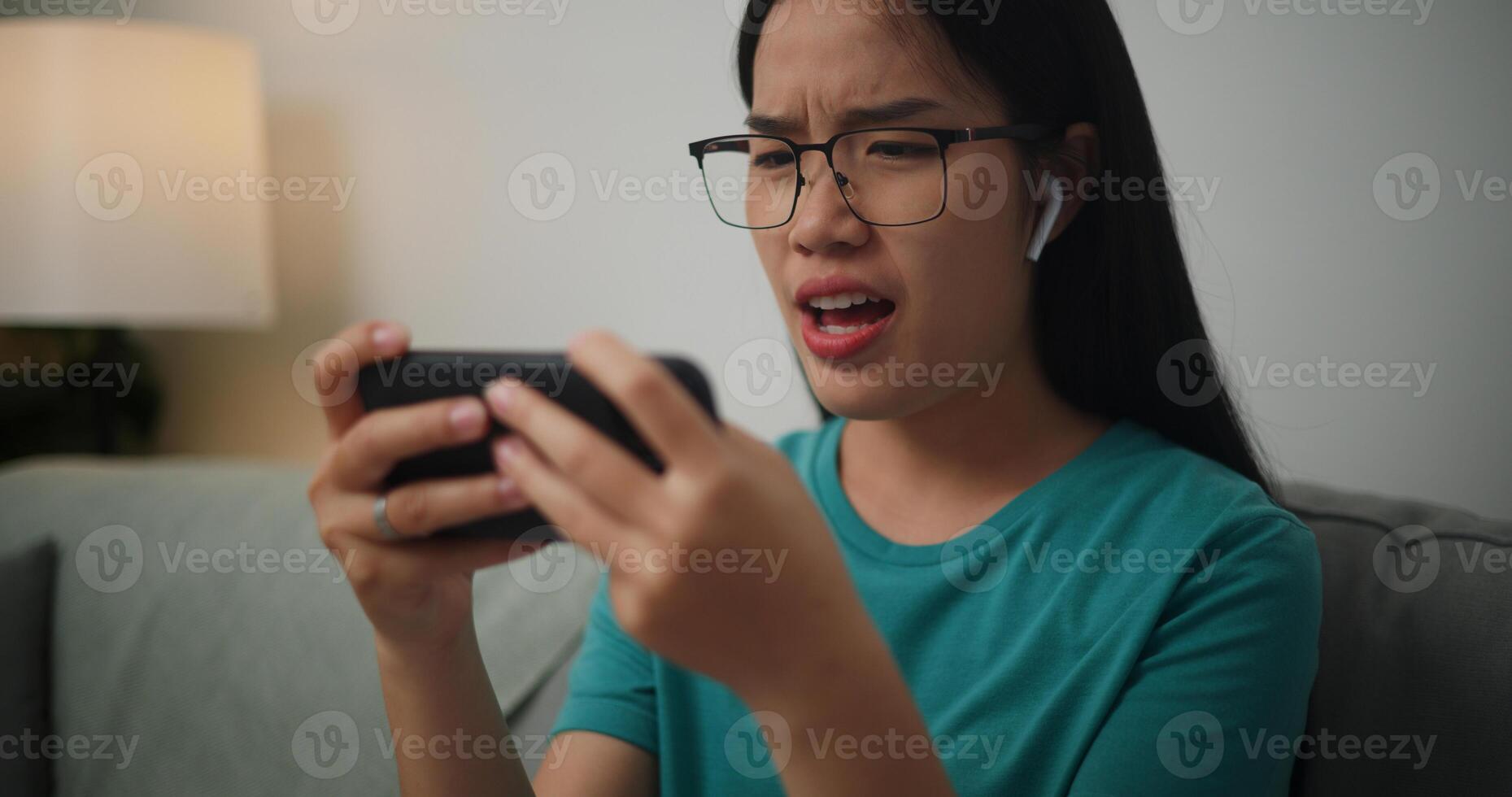 ritratto di giovane asiatico donna grave giocando un in linea gioco frustrato con perdita o fallimento seduta su divano nel vivente camera a home.gamer stile di vita concetto. foto