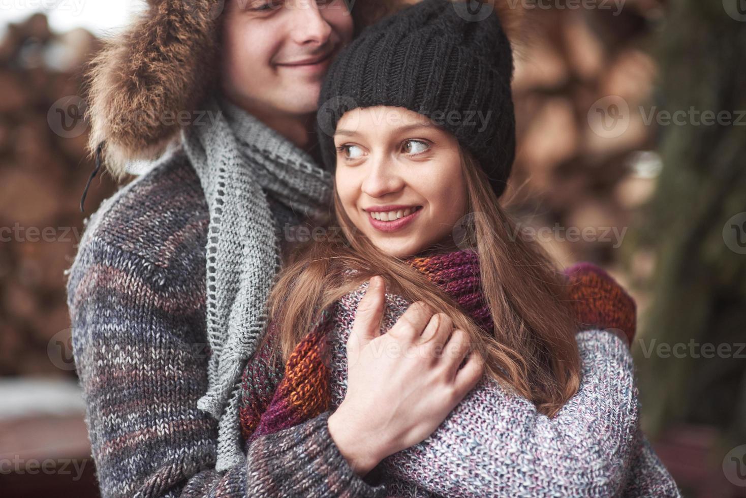 mezzo busto ritratto di giovane uomo spensierato e donna che si abbracciano e sorridono. sono in piedi nella foresta invernale e guardano la telecamera con felicità foto