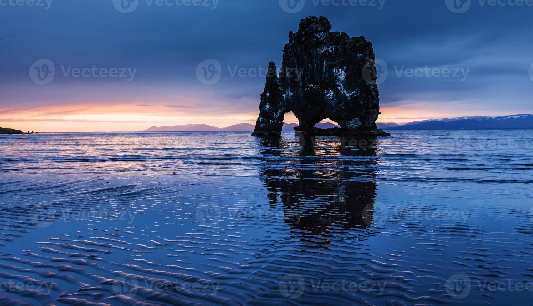 è una spettacolare roccia nel mare sulla costa settentrionale dell'Islanda. le leggende dicono che è un troll pietrificato. in questa foto hvitserkur si riflette nell'acqua del mare dopo il tramonto di mezzanotte