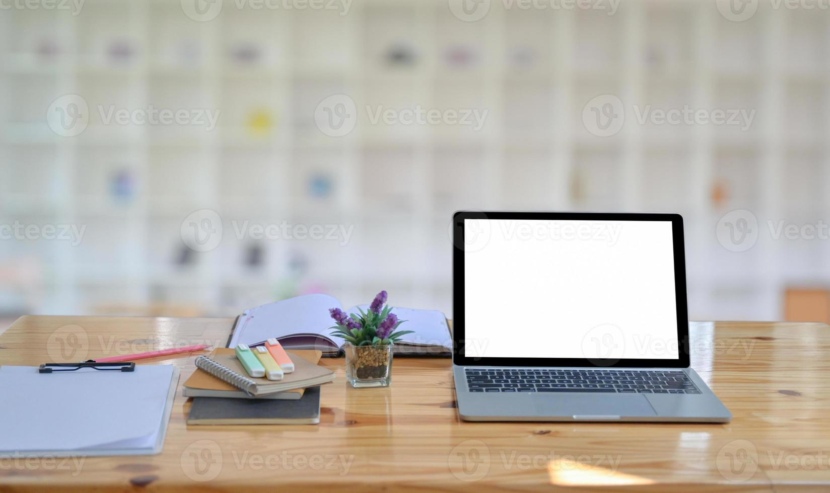 un laptop e un notebook con cancelleria sono posizionati sul tavolo nella comoda postazione di lavoro. foto