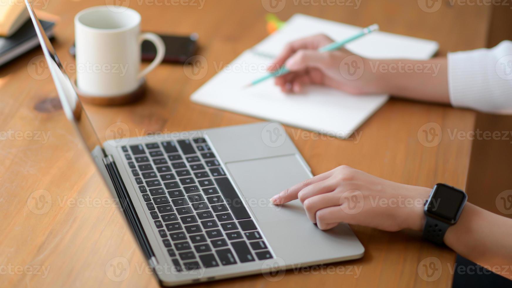 la mano di una giovane donna che usa un laptop e scrive una relazione, lavora da casa. foto