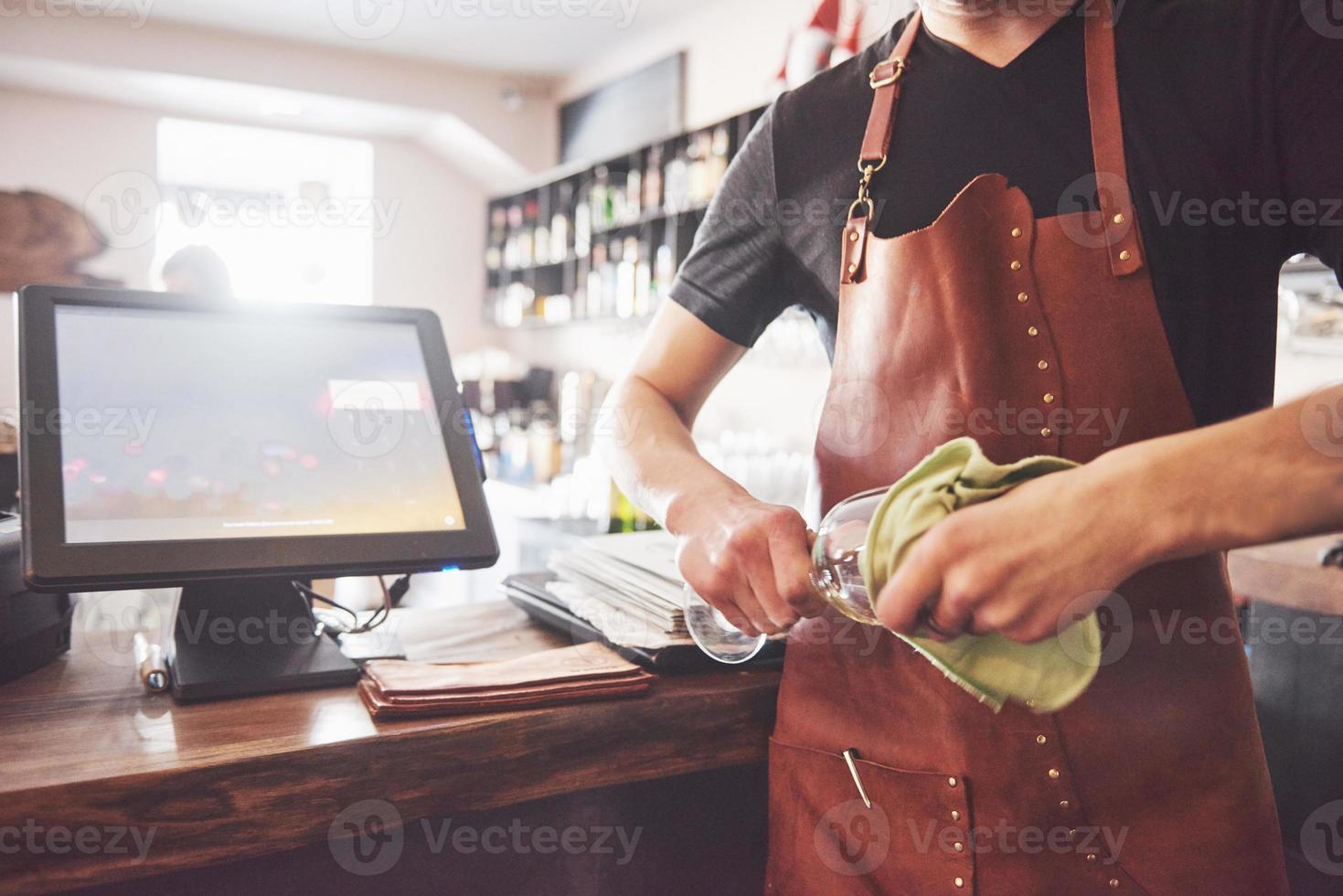 barman nell'interiore del bar che fa cocktail alcolici. il barista professionista versa la bevanda con un colino foto