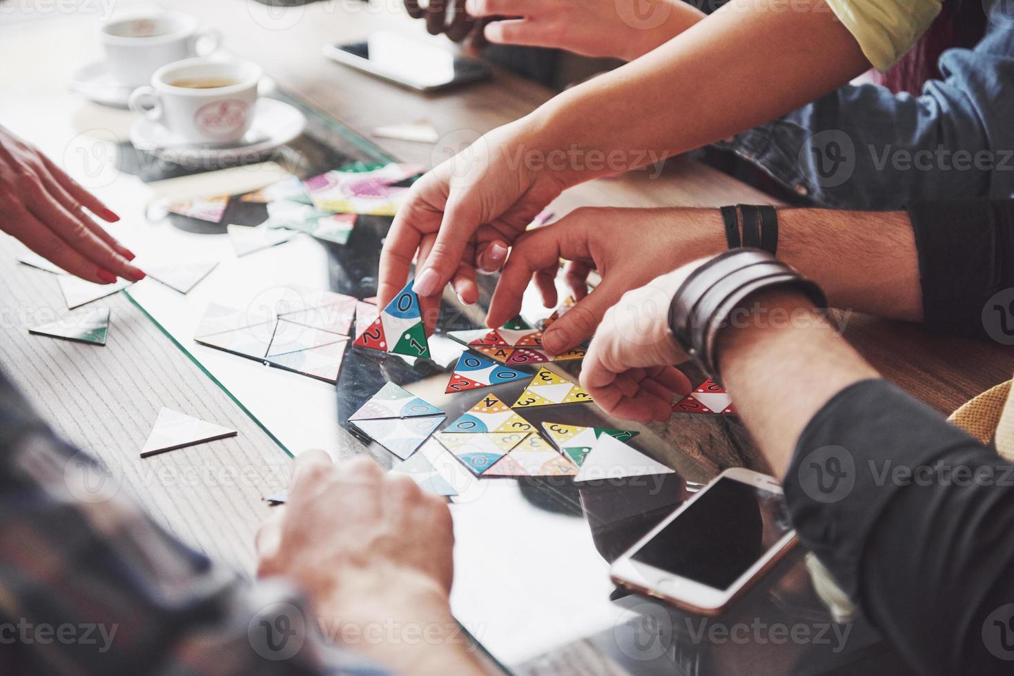 gruppo di amici creativi seduti al tavolo di legno. persone che si divertono mentre giocano a giochi da tavolo foto