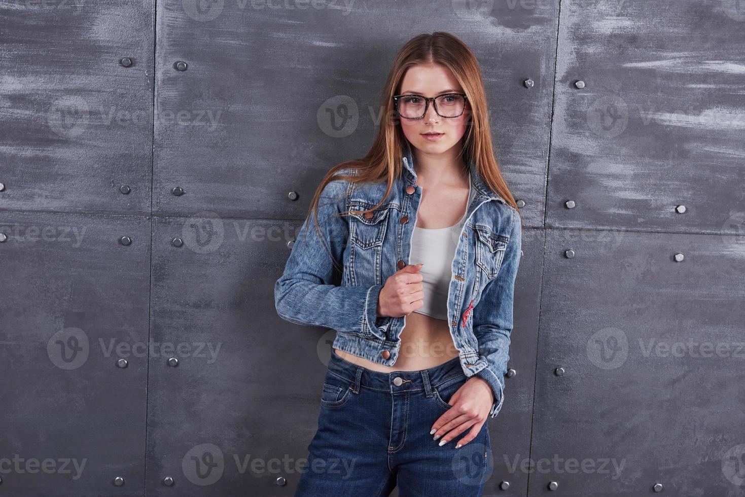 moda, abbigliamento, concetto di persone. attraente giovane donna sexy con giacca di jeans. la ragazza sta posando in studio foto