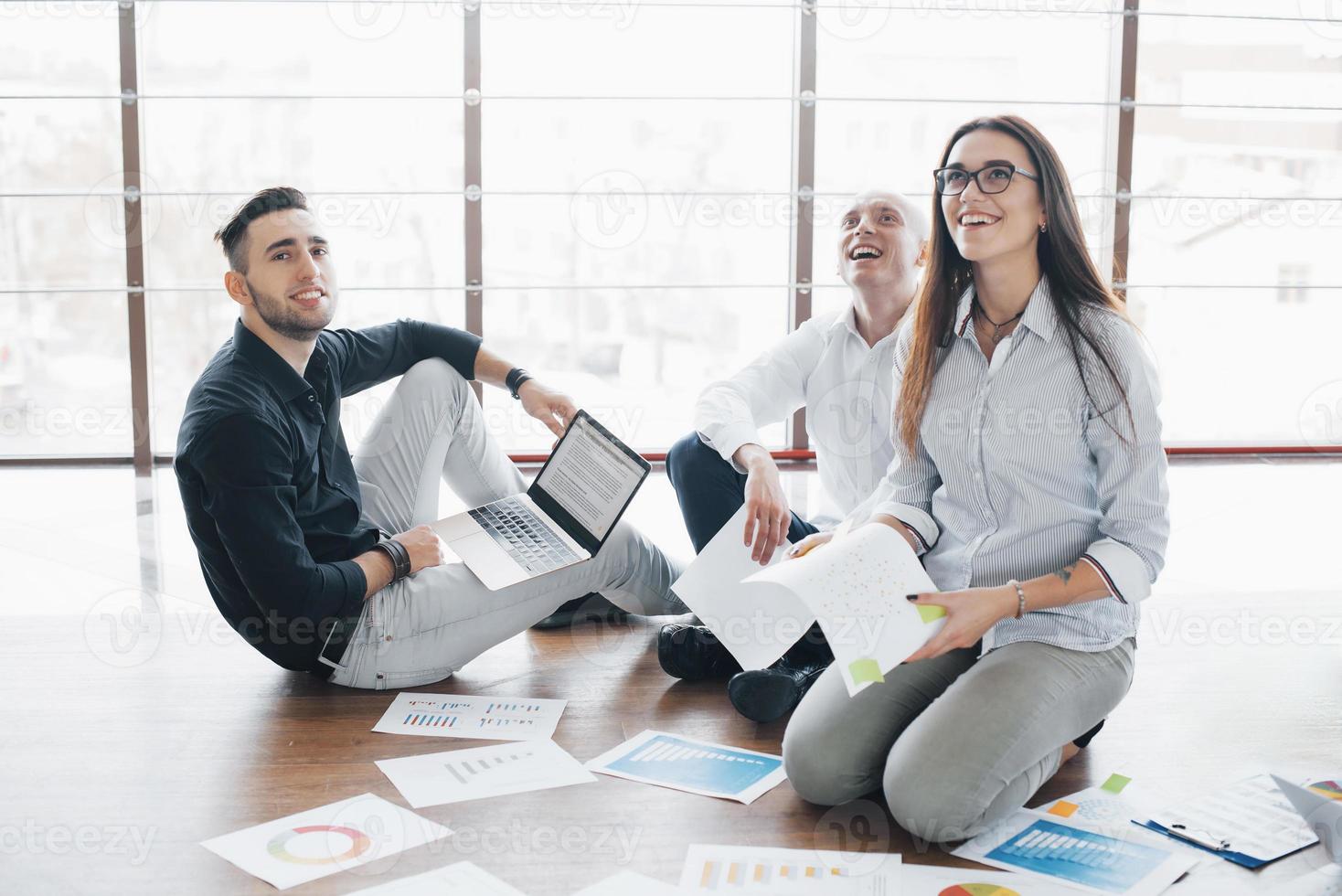 strategia di pianificazione insieme. team aziendale guardando i documenti sul pavimento con il manager che punta a un'idea. cooperazione aziendale successo. disegno di pianificazione disegnare. concetto di lavoro di squadra foto