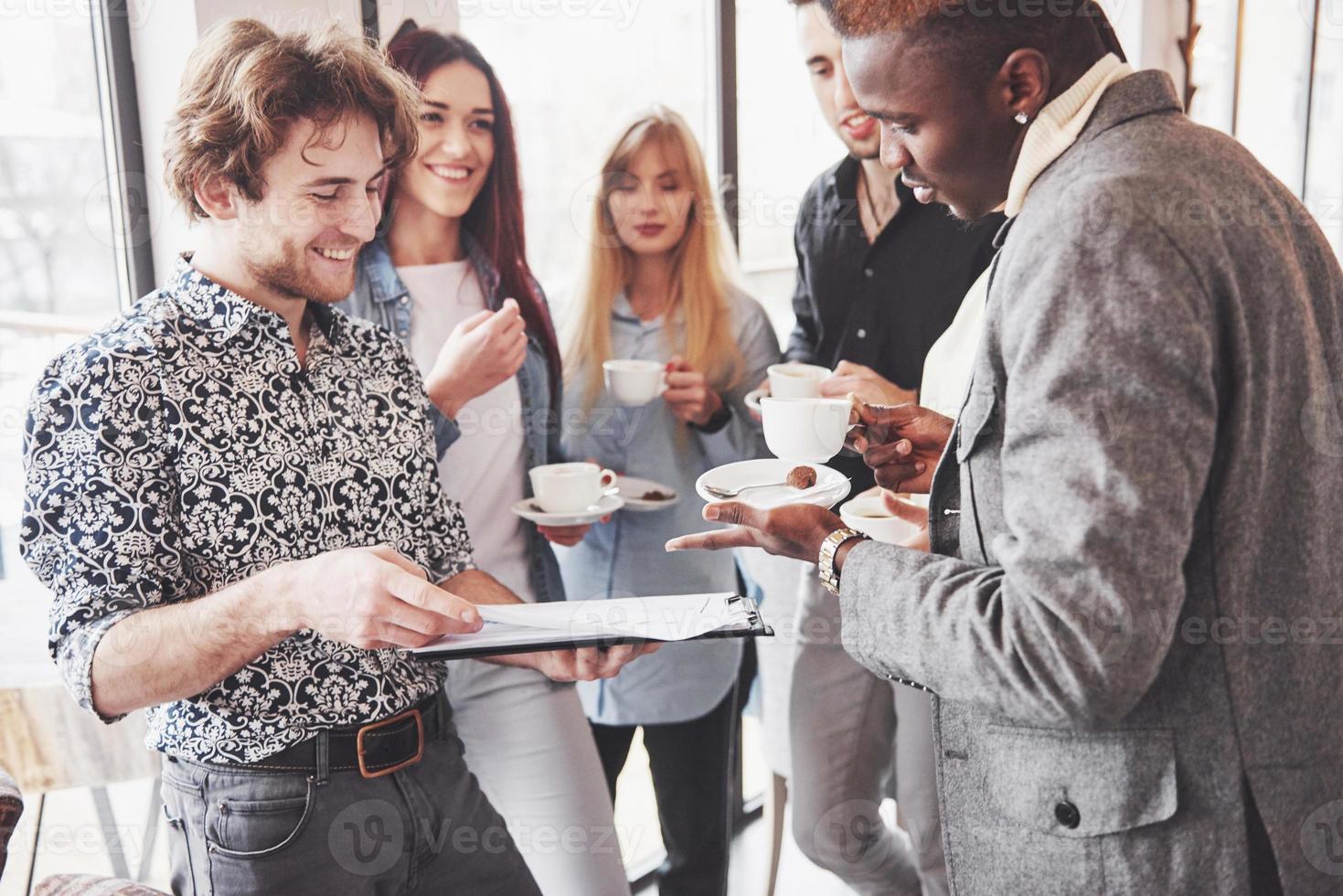 giovani imprenditori di successo parlano e sorridono durante la pausa caffè in ufficio foto