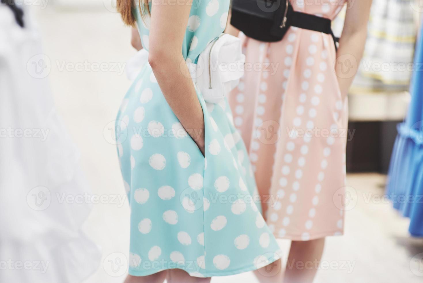 shopping therapy in azione. vista posteriore di due belle donne con borse della spesa che si guardano con un sorriso mentre camminano al negozio di abbigliamento foto