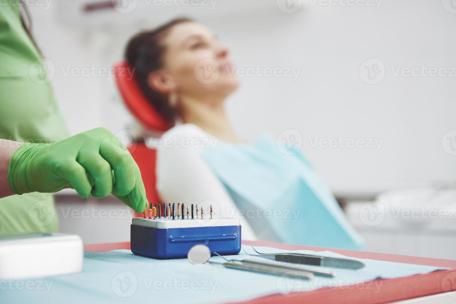 un paziente in una clinica odontoiatrica si siede su una sedia e il medico prepara gli strumenti per il trattamento foto